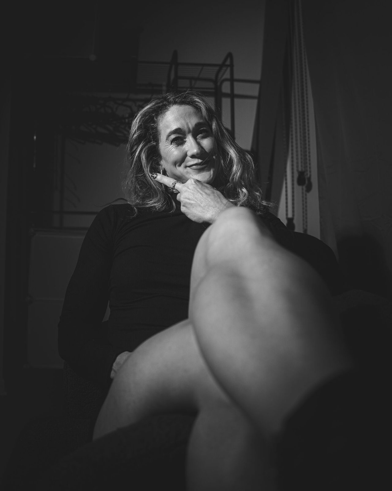 Low-key black and white portrait, hand to chin, emerging from shadow