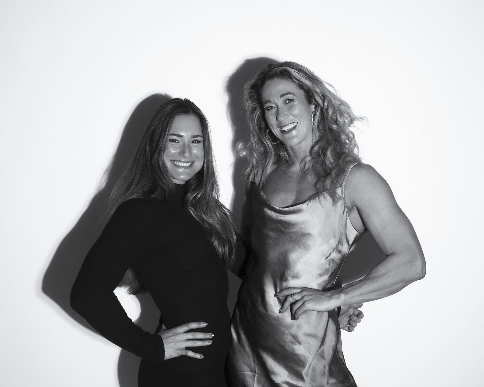 High-key black and white portrait of two women, both with hands on hips