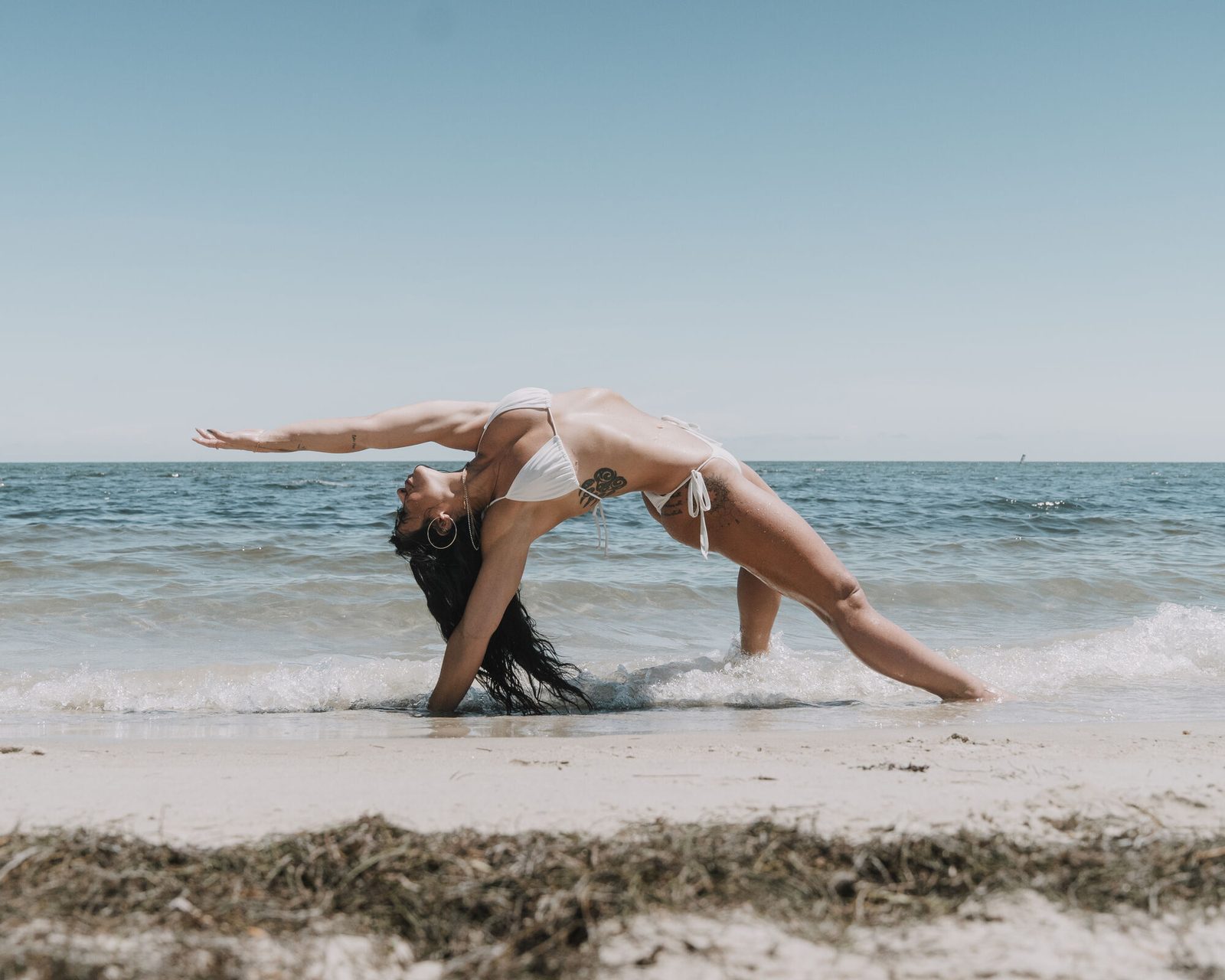 Backbend at the water's edge with one arm extended