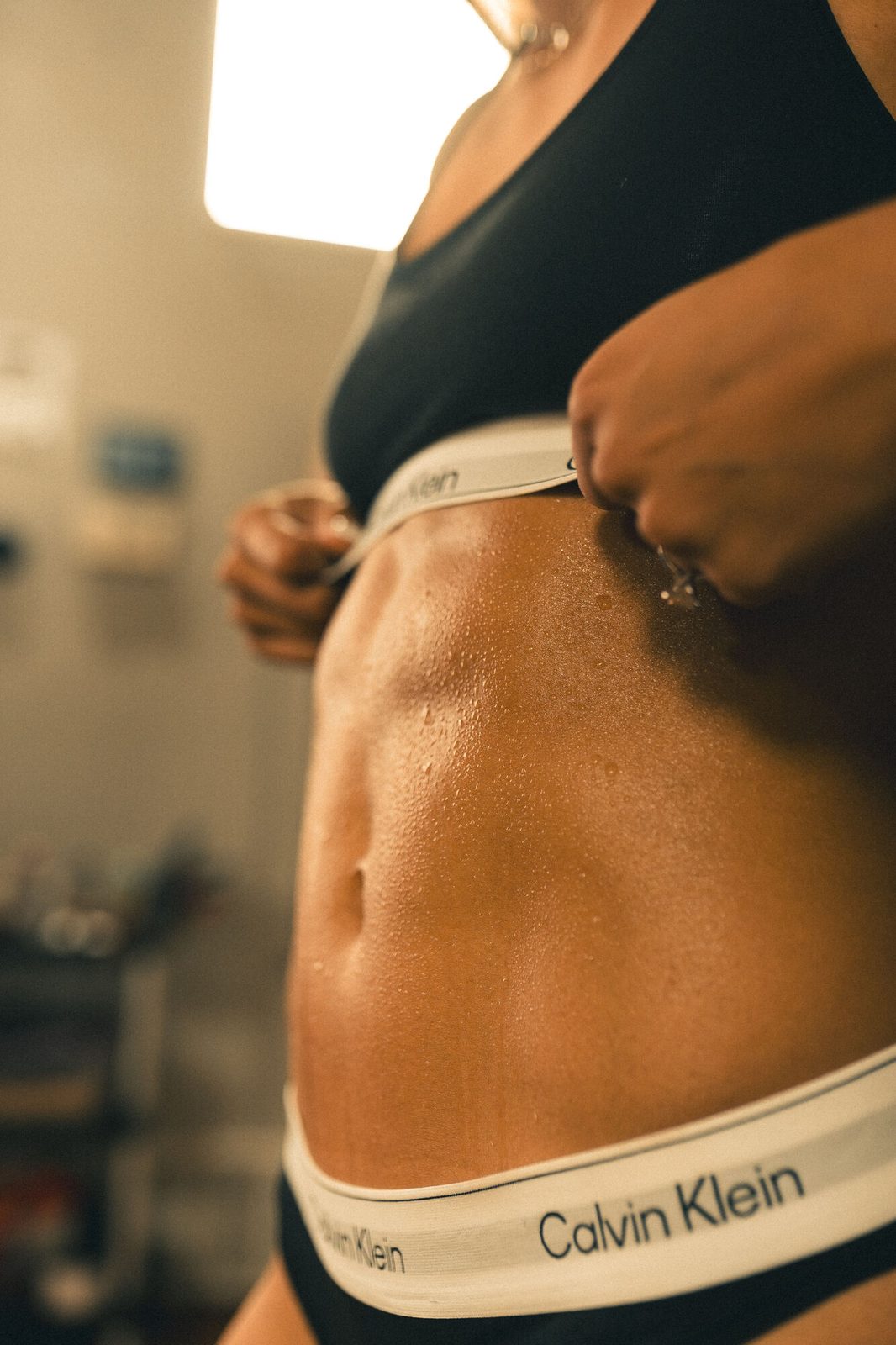 Warm window-lit core detail, hand at the waistband