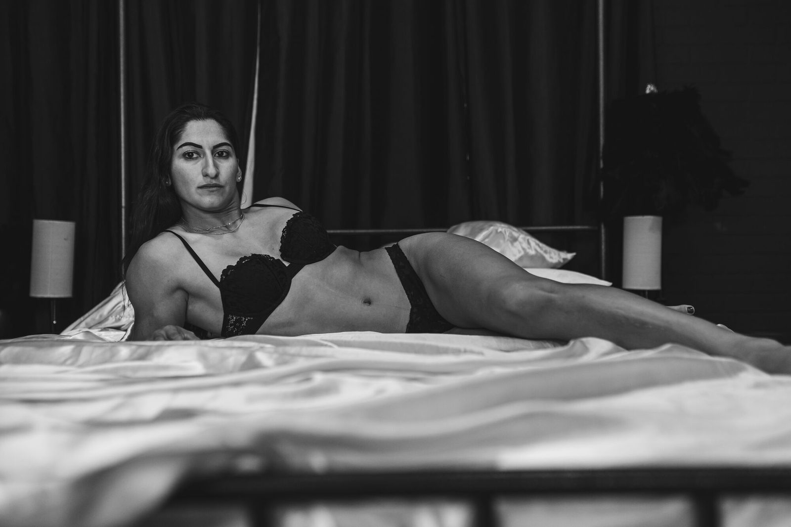 Black and white, reclining on white linen with a calm direct gaze